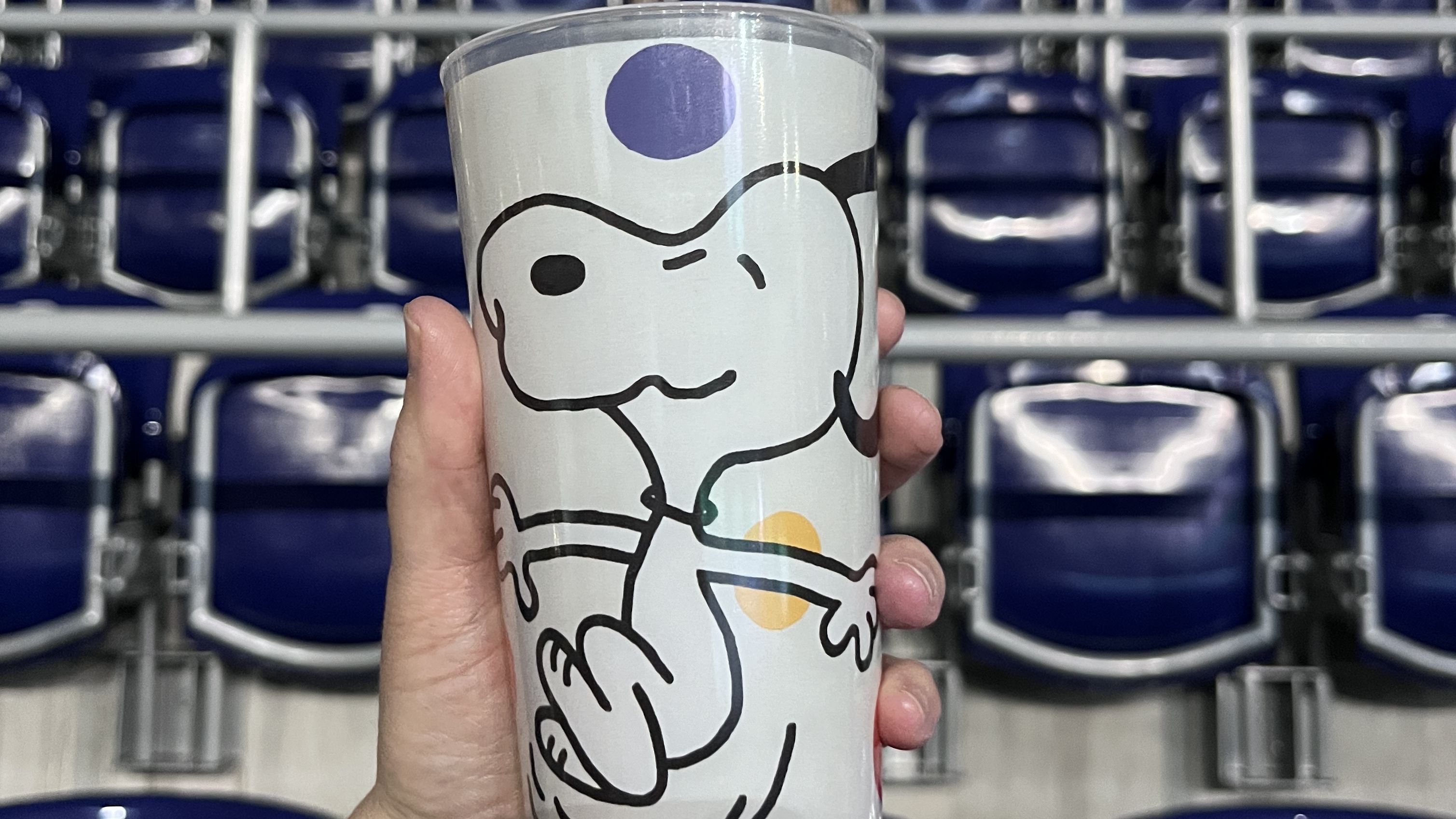 Eine Hand mit einem Mehrwegbecher, auf dem Snoopy zu sehen ist. 