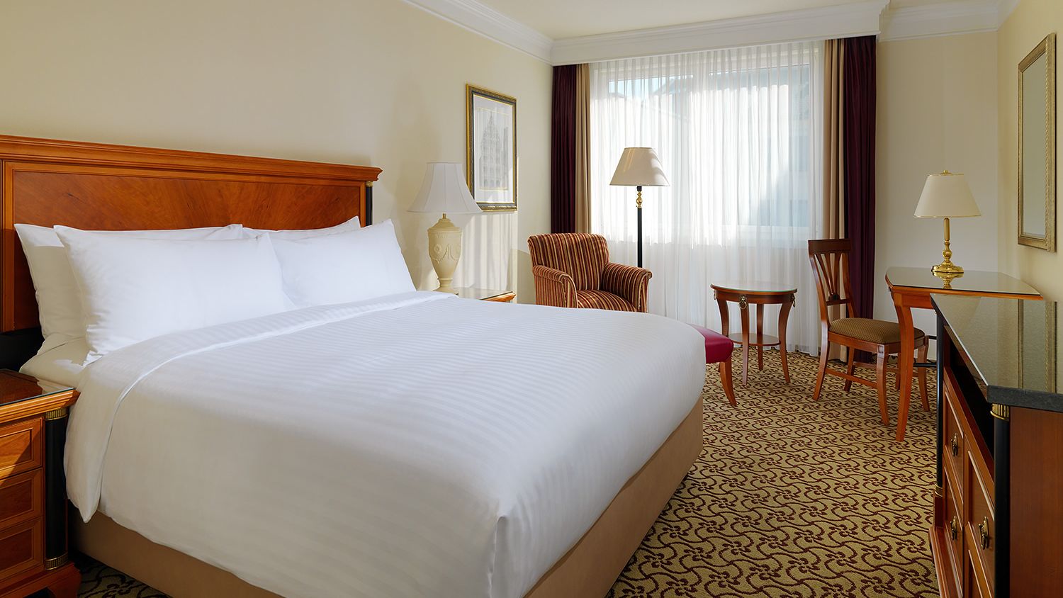 Helles Hotelzimmer mit großem Bett und Schreibtisch.