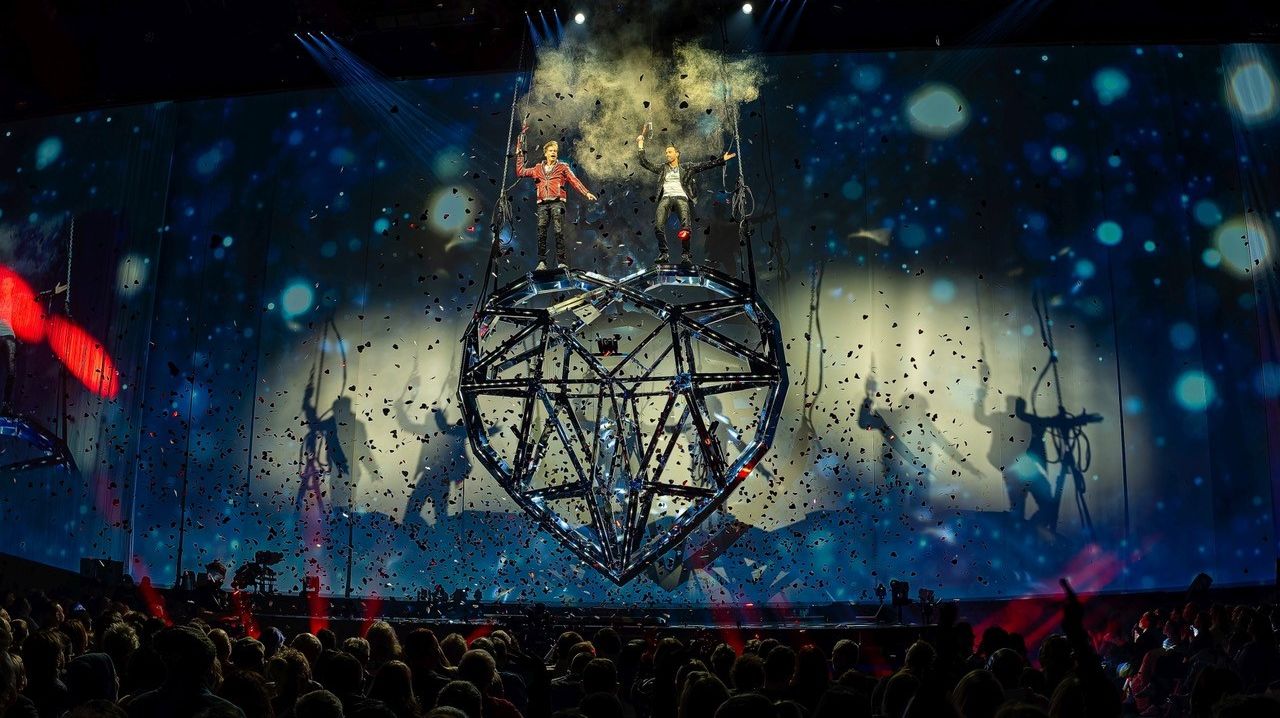 Die Ehrlich Brothers stehen auf einem großen Herz aus Stahl, es regnet Konfetti. 