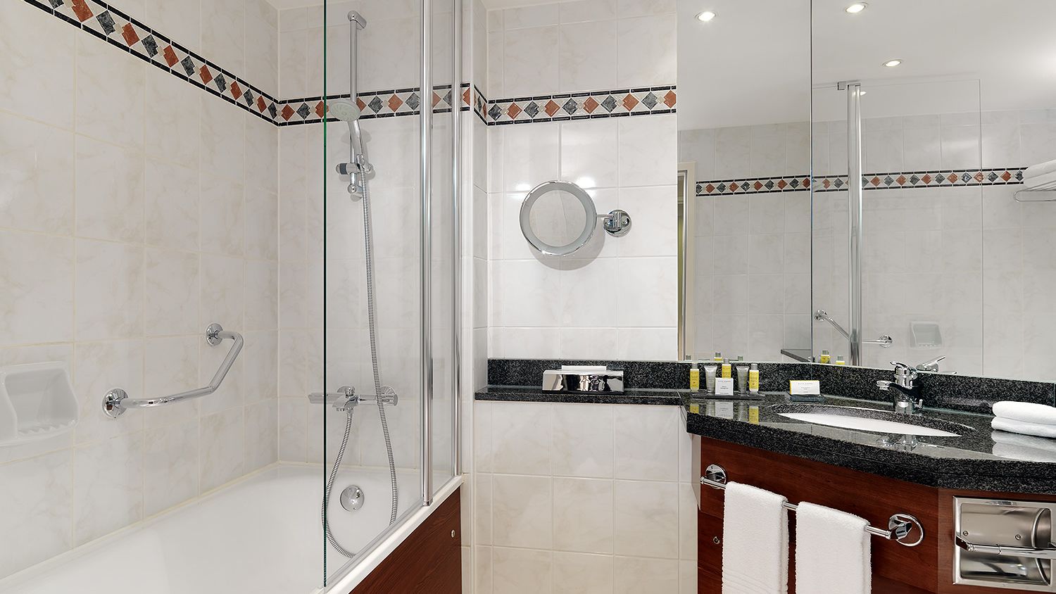 Badezimmer mit Waschbecken, Spiegeln und Badewanne mit Dusche.