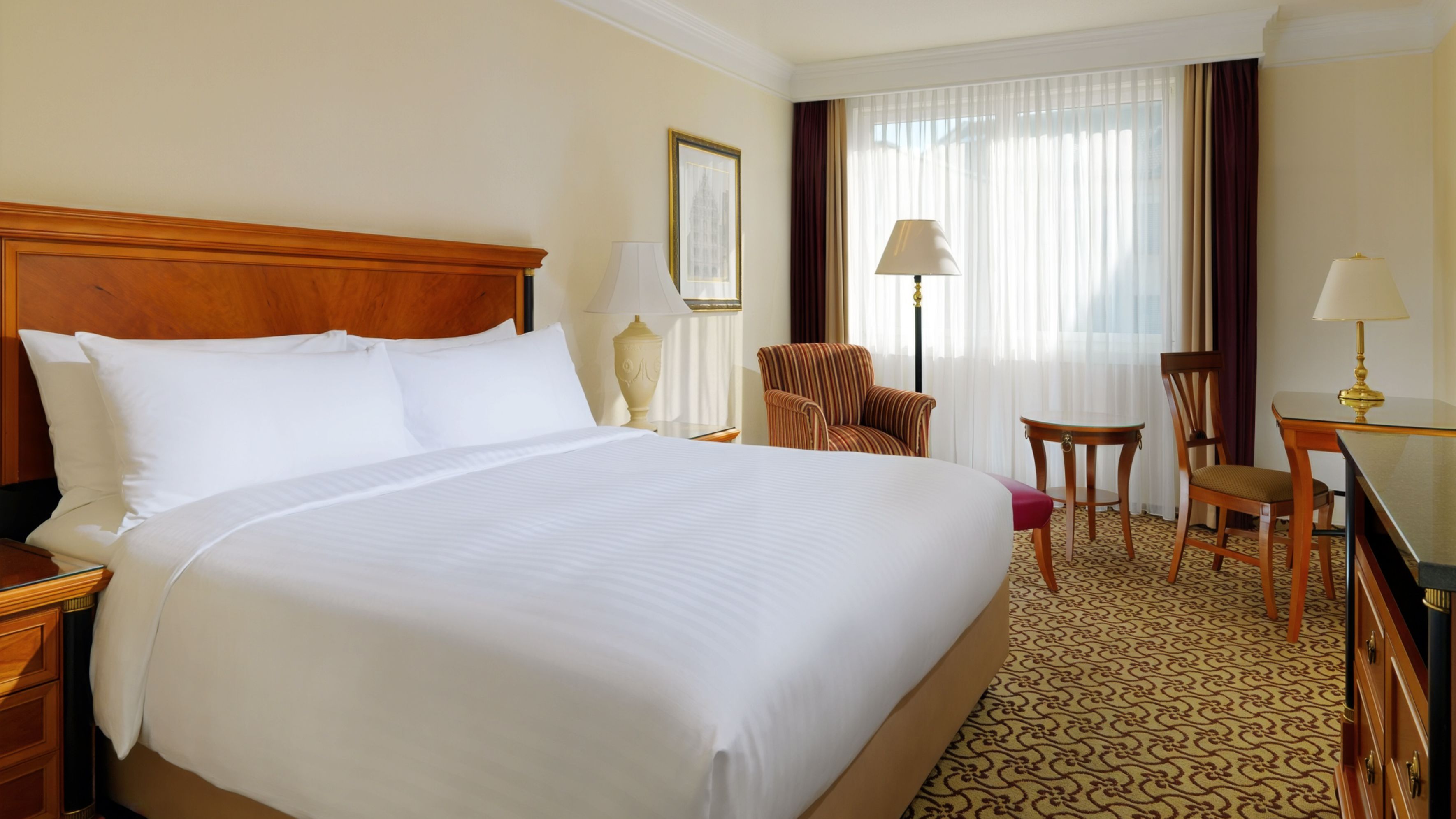 Helles Hotelzimmer mit großem Bett und Schreibtisch.