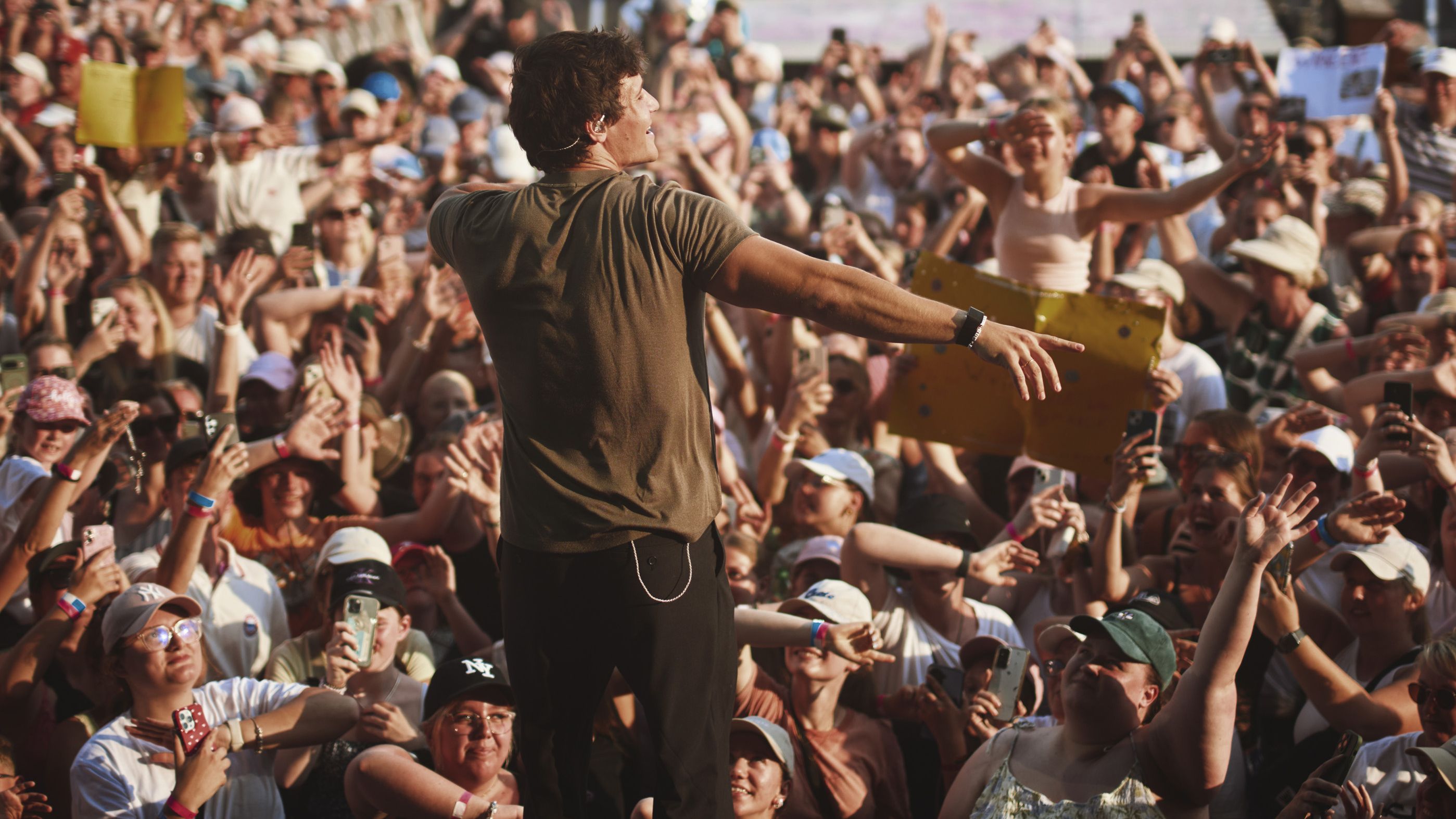 Es ist ein Bild von einem Live-Open-Air-Konzert, fotografiert mit Blick von der Bühne aufs Publikum. Wincent Weiss ist von hinten zu sehen. 