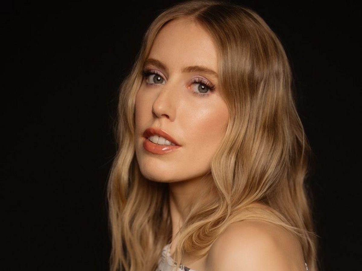 Pressefoto von LEA. Sie steht seitlich, hat den Kopf zur Kamera gedreht. Sie trägt ein schulterfreies Top, ihre langen, blonden Haare sind offen. 