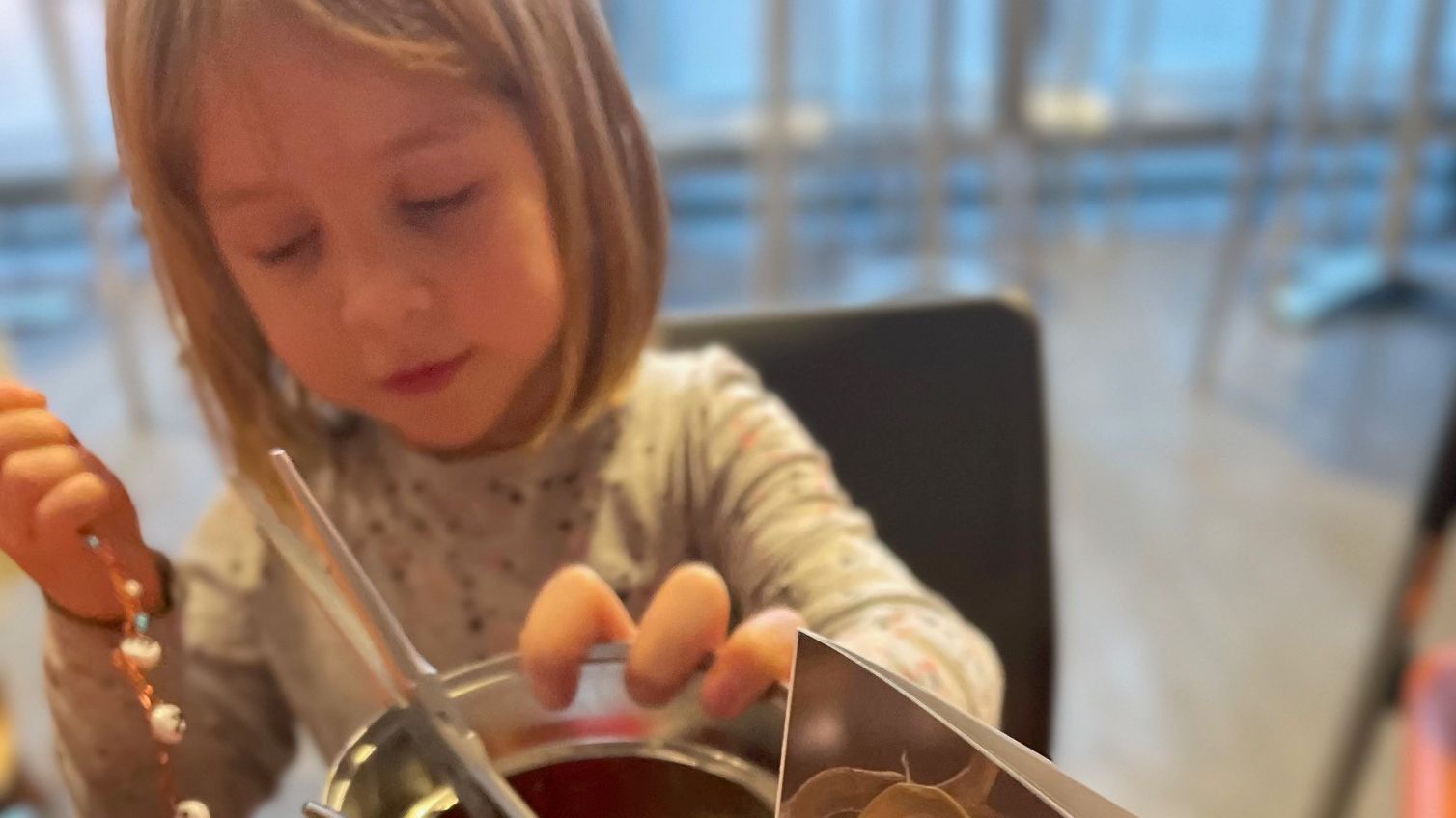 Ein Mädchen bastelt an einem Tisch, auf dem Bastelmaterialien stehen. 