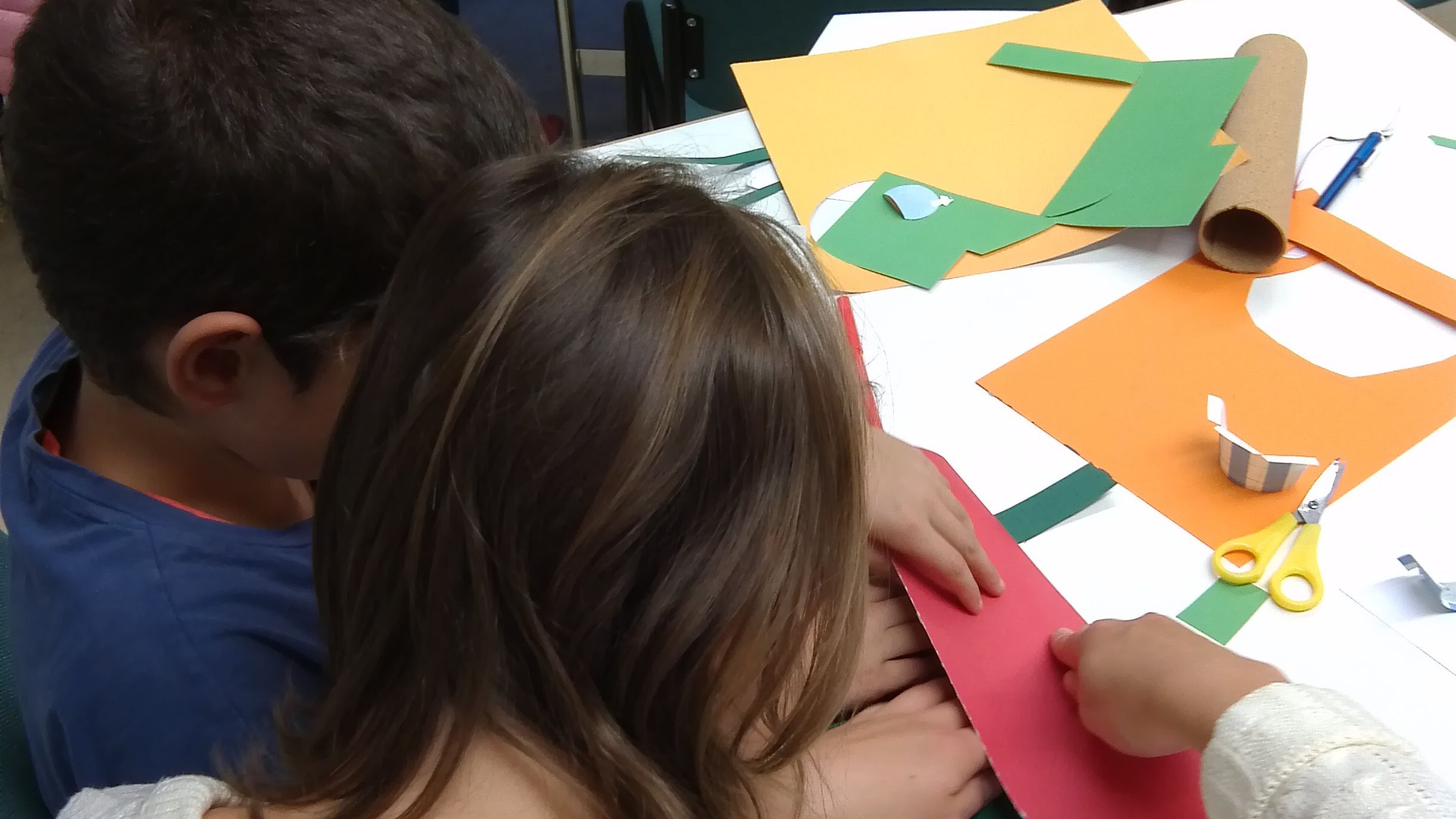 Zwei Kinder sitzen an einem Tisch und basteln. 