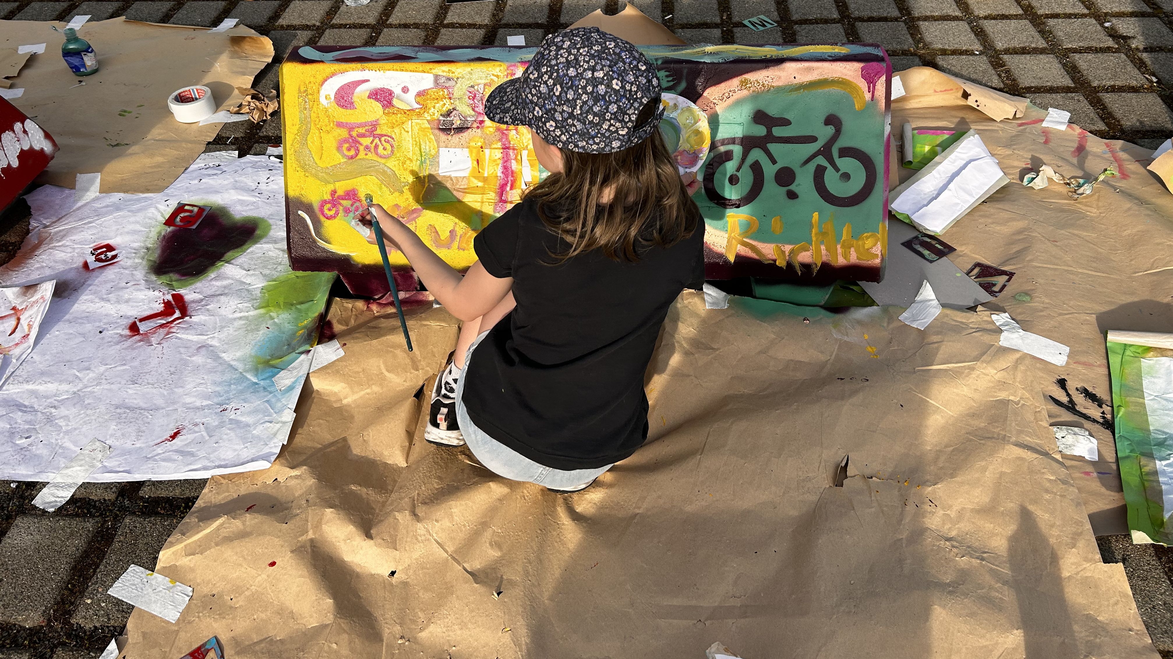 Ein Kind beim Bemalen eines Parkplatz-Pollers. 