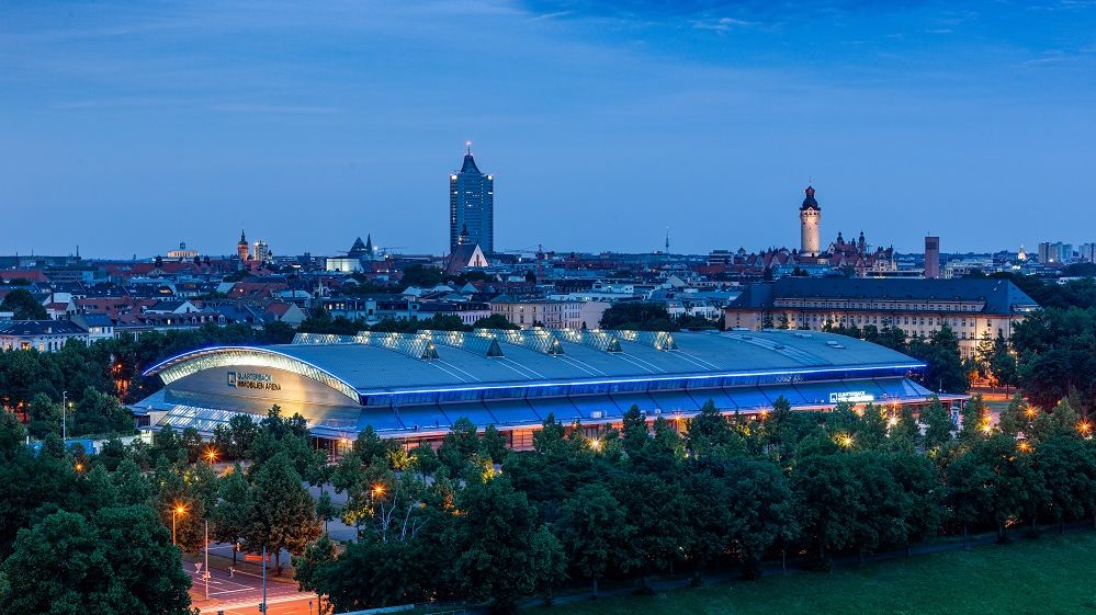 Blick auf die QUARTERBACK Immobilien ARENA am Abend vor der Skyline von Leipzig.