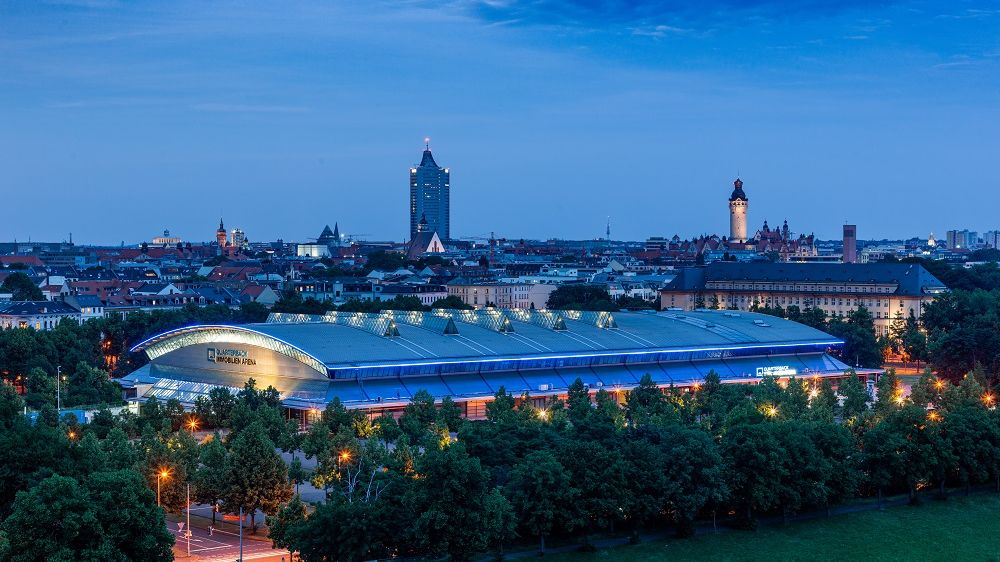 Blick auf die QUARTERBACK Immobilien ARENA am Abend vor der Skyline von Leipzig.
