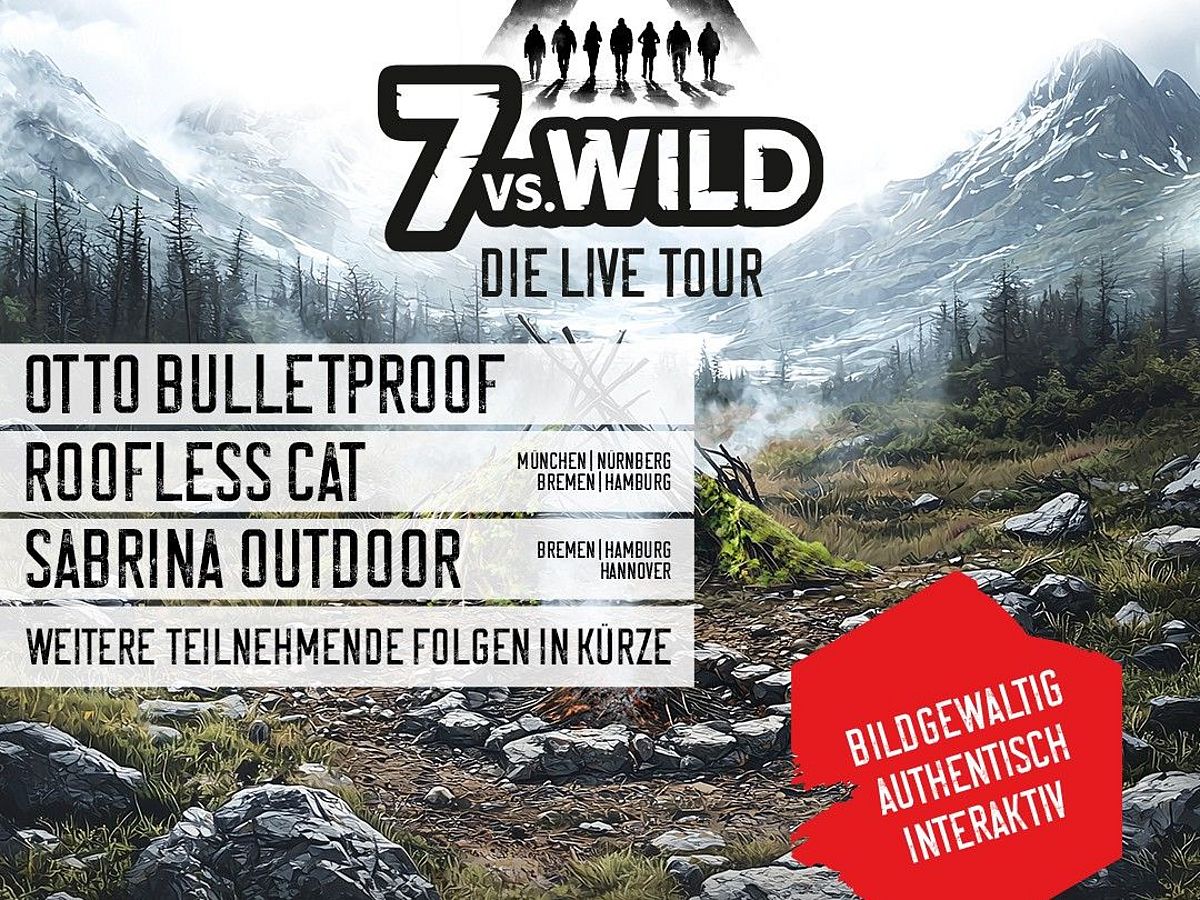 Im Vordergrund ist eine Feuerstelle mit einer selbstgebauten Holthütte zu sehen. Im Hintergrund sind Berge, die schneebedeckt sind. 