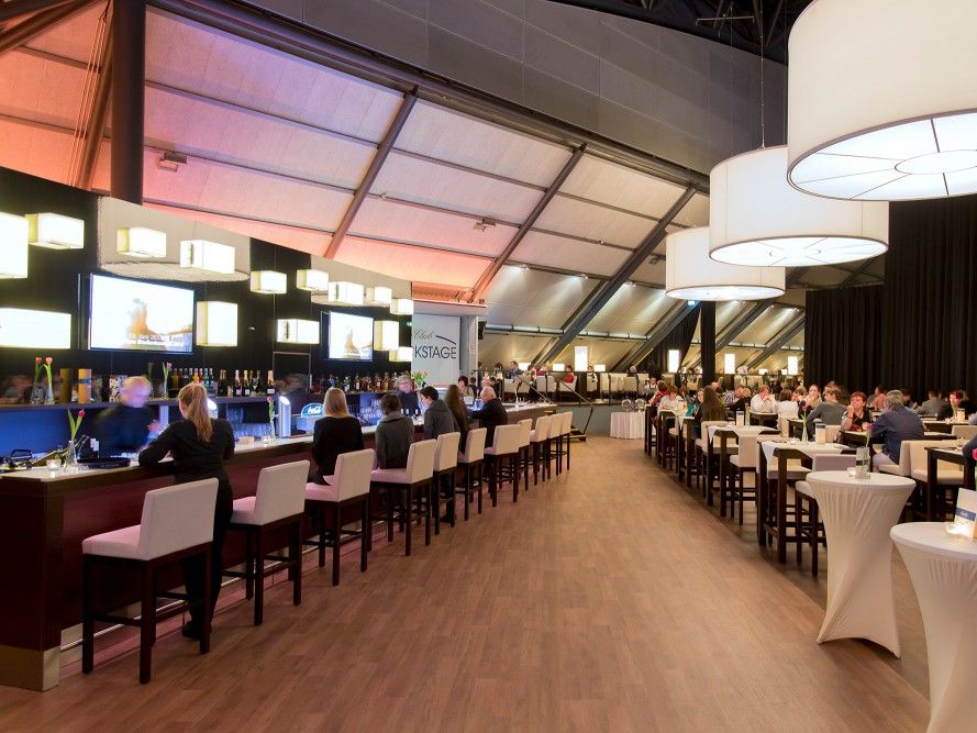 Blick in den besuchten BACKSTAGE CLUB mit moderner Bar, Sitzgelegenheiten und Stehtischen.