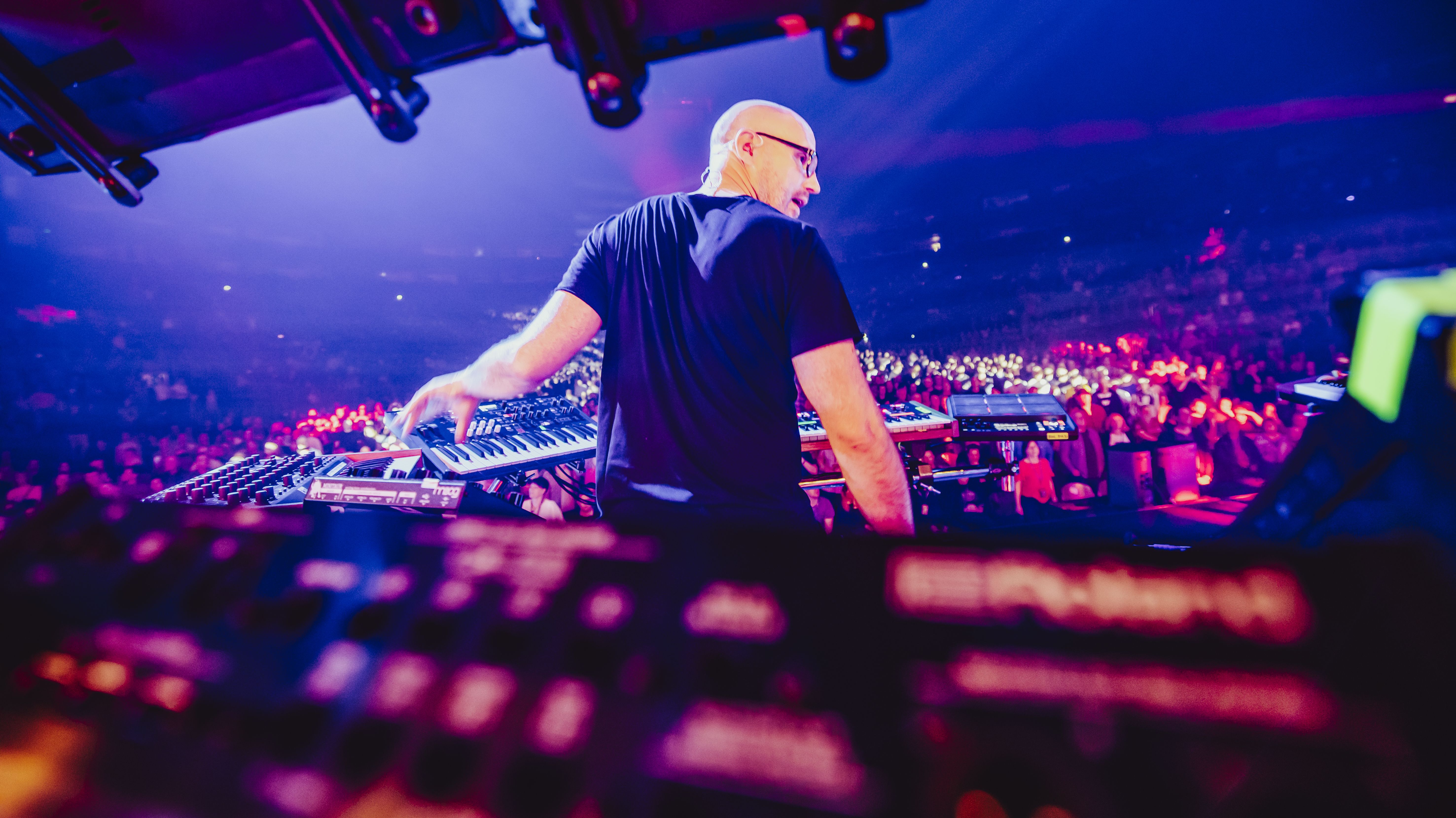 Schiller steht hinter Synthesizern. Im Hintergrund steht das Publikum. 
