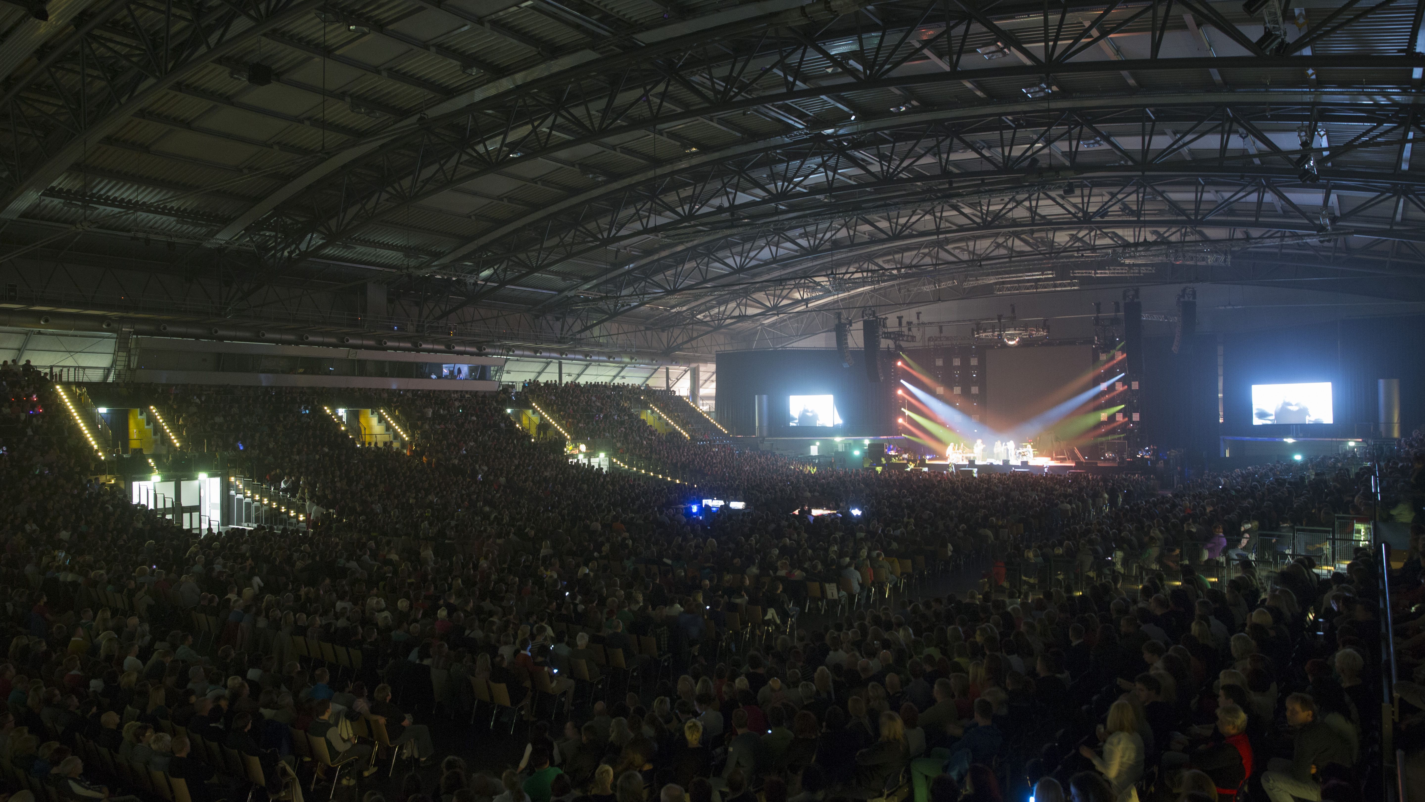 Blick in die gut besuchte QUARTERBACK Immobilien ARENA mit beleuchteter Bühne.