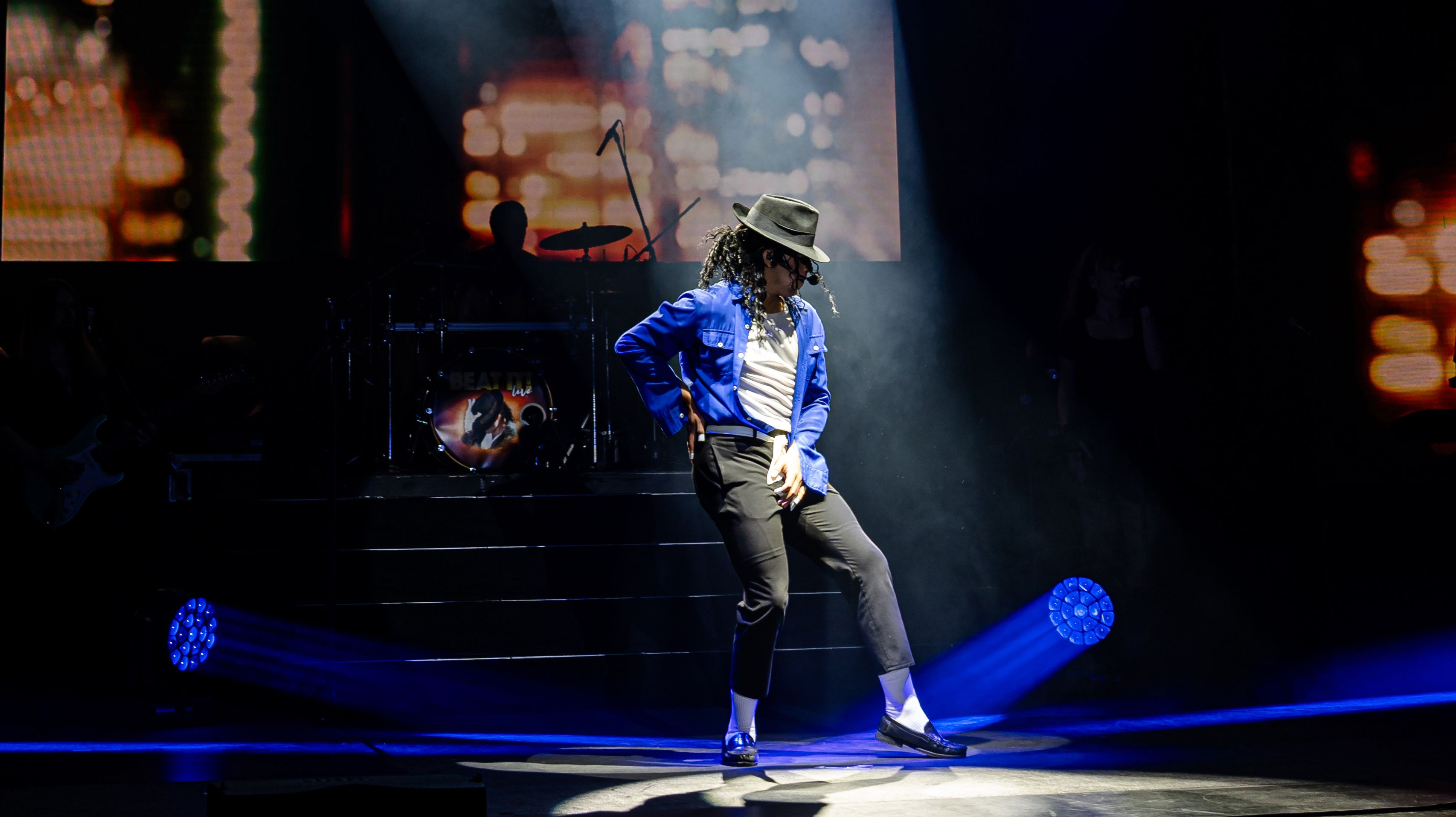 Der Michael Jackson Darsteller steht auf der Bühne, trägt einen Hut und greift sich beim Tanzen in den Schritt.