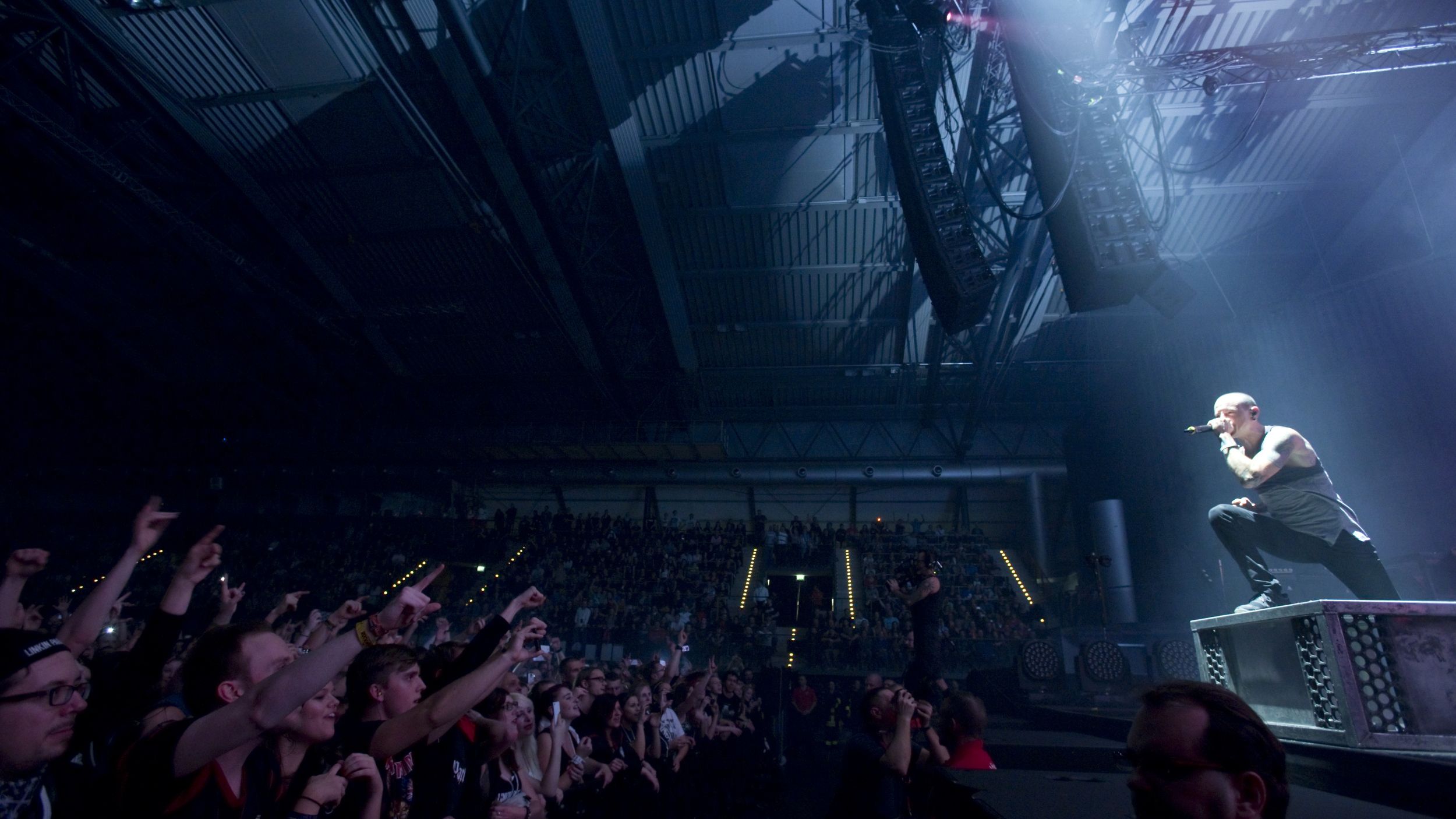 Sänger am Mikrofon beugt sich von der Bühne in Richtung des jubelnden Publikums.