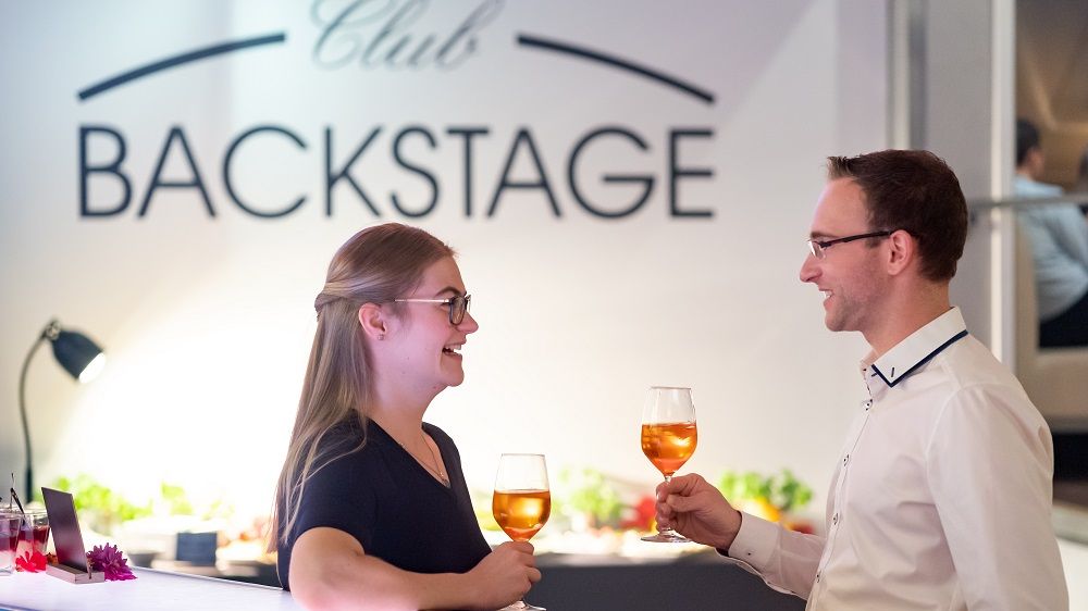 Ein Pärchen stößt mit einem Getränk an.