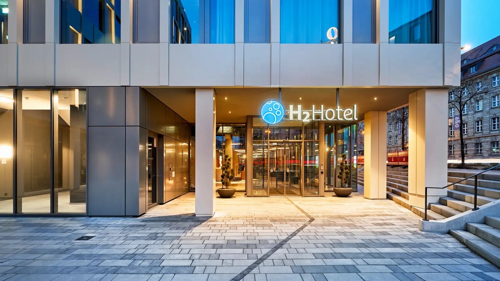 Außenansicht des H2 Hotels bei Nacht mit Beleuchtung. 