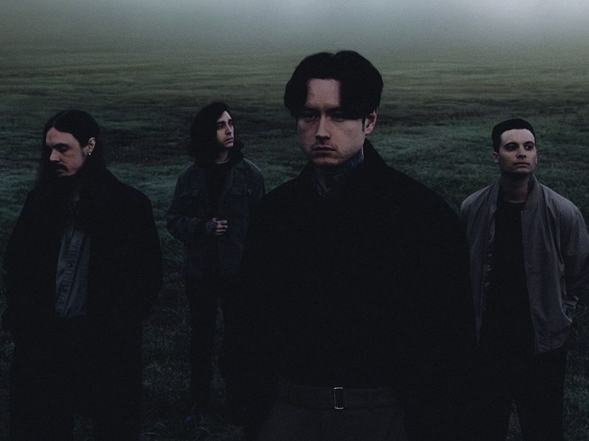 Die Band stehen verteilt auf einem Feld, es ist dunkler und neblig. Alle schauen in unterschiedliche Richtungen. 