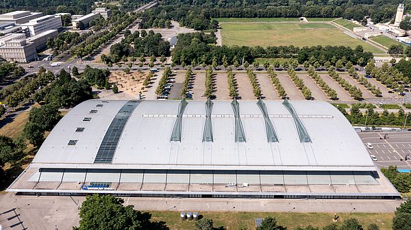 Luftbild der QUARTERBACK Immobilien ARENA bei gutem Wetter. Zu sehen ist neben der Halle, der Parkplatz sowie die Festwiese Leipzig. 