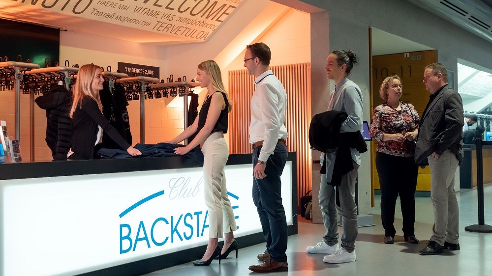 Leute geben am Empfangstresen des BACKSTAGE CLUB ihre Garderobe ab.