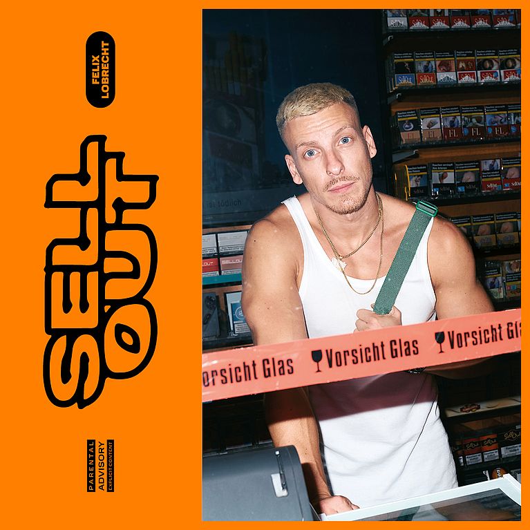 Felix Lobrecht trägt ein Unterhemd und zwei Goldketten. Er steht in einem Kisok. 