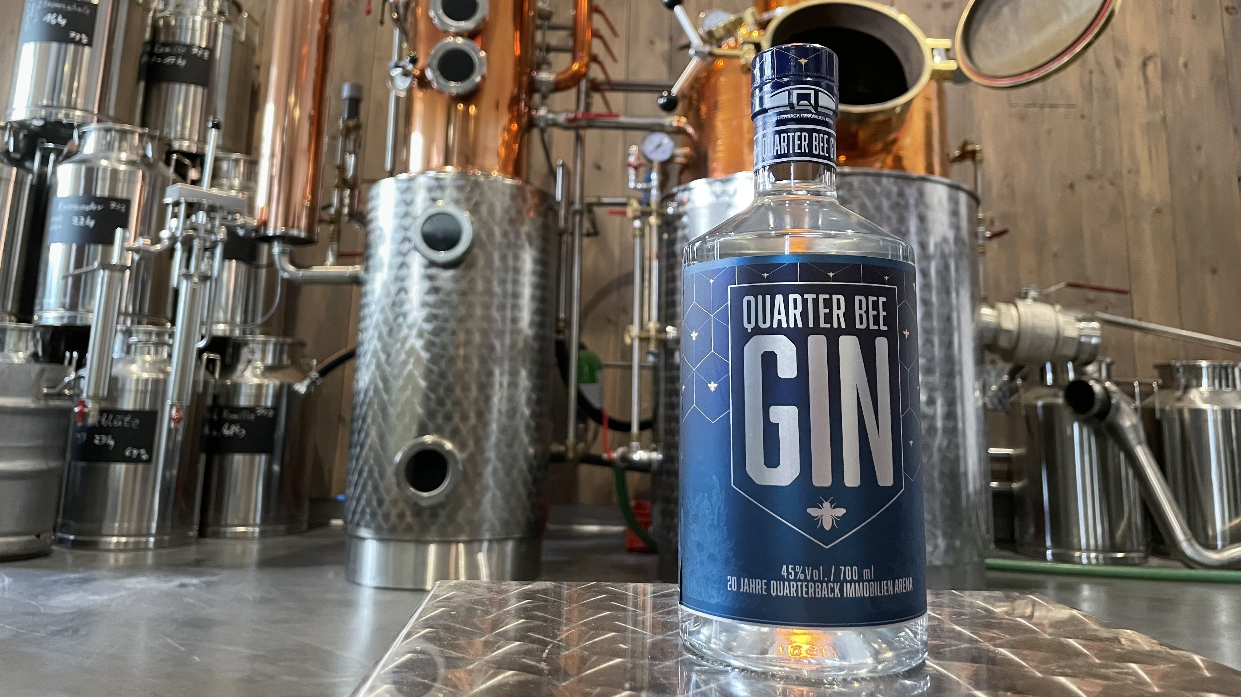 Eine gefüllte Gin-Flasche vor dem Destilliergerät. 