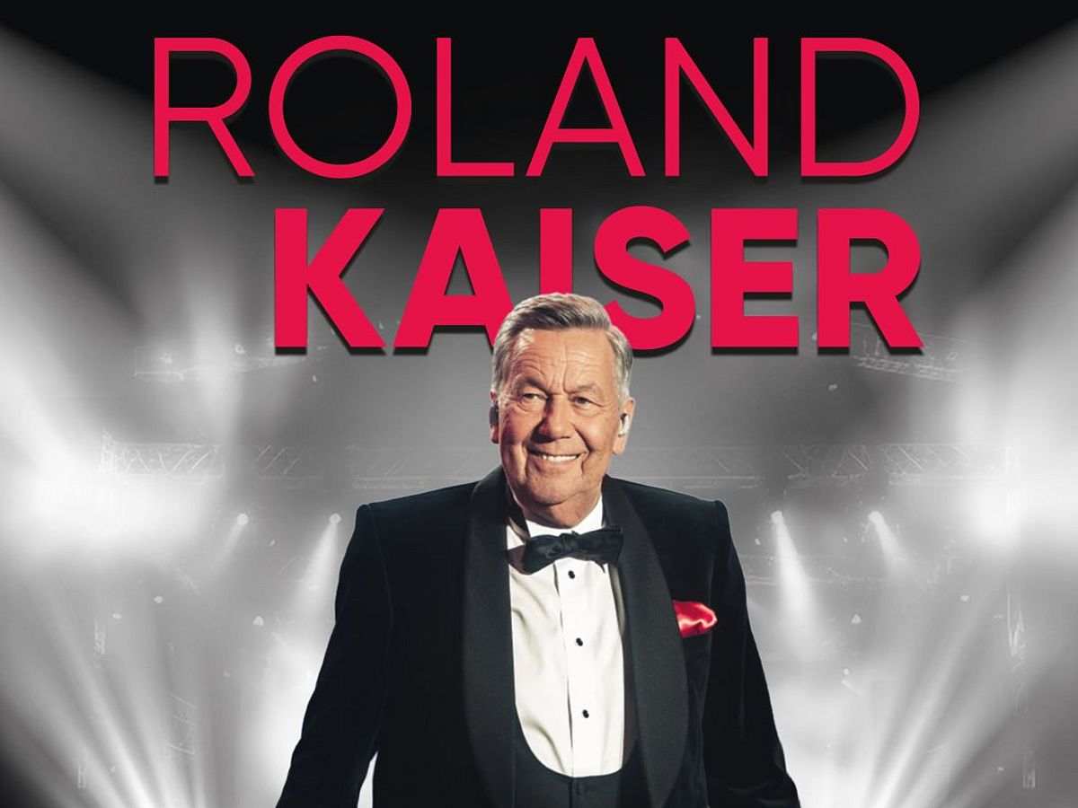 Eine Tourgrafik zeigt Roland Kaiser im Anzug vor einer erleuchteten Bühne und es wird seine Arena Tour 2027 mit dem Titel "Unser Moment" angekündigt.