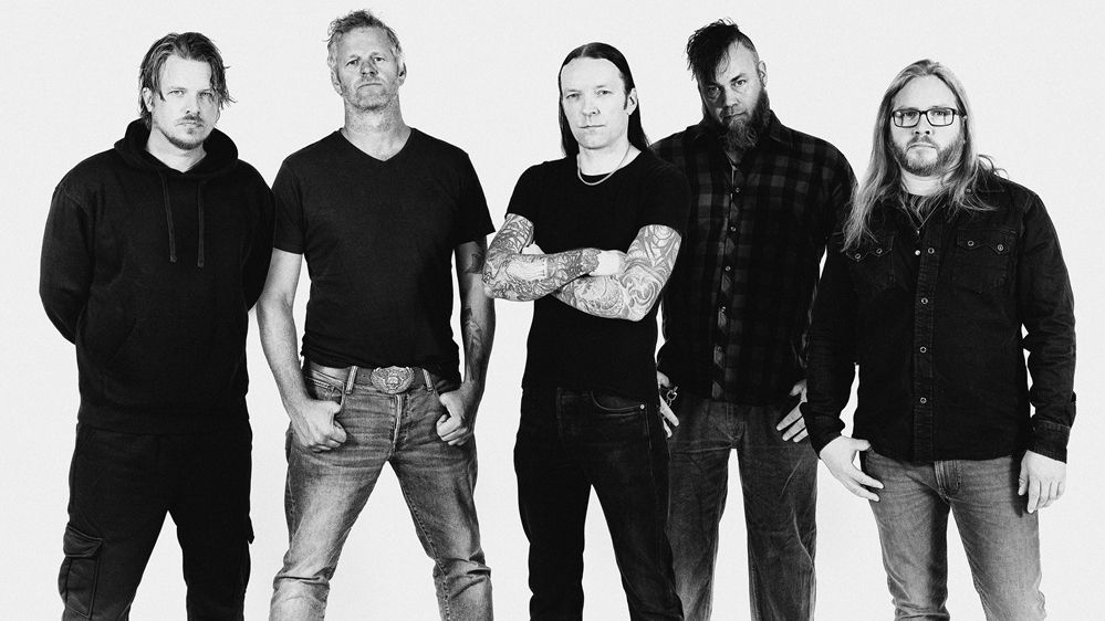 Schwarz-weiß Pressebild der Band. Es sind fünf Männer, die alle Jeans mit einem dunklen Oberteil tragen. Zwei haben lange Haare, drei einen Bart. 