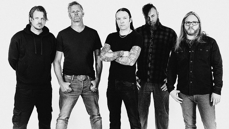 Schwarz-weiß Pressebild der Band. Es sind fünf Männer, die alle Jeans mit einem dunklen Oberteil tragen. Zwei haben lange Haare, drei einen Bart. 