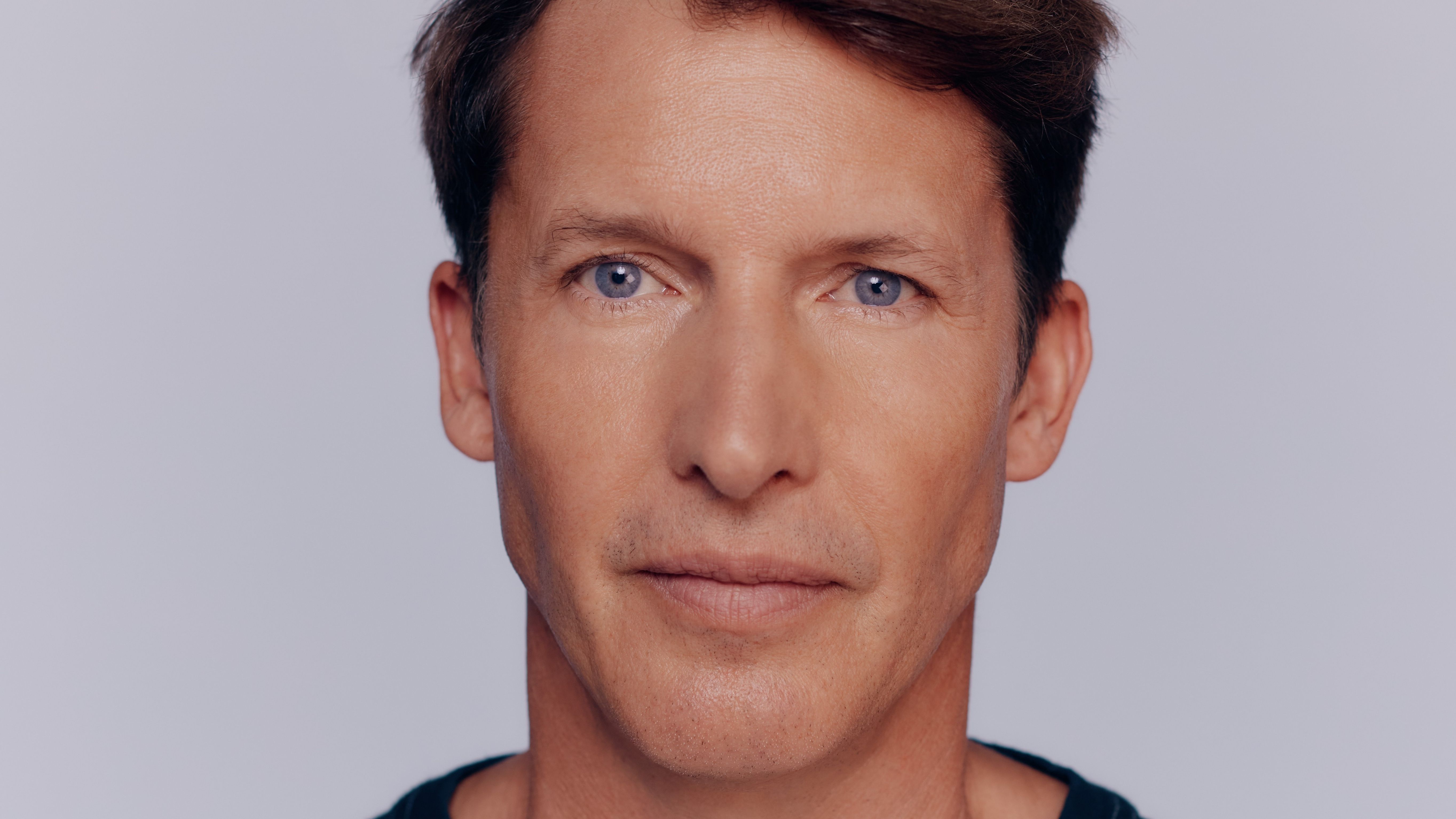 Pressebild von James Blunt. Es ist mur sein Gesicht zu sehen, er steht vor einem hellen Hintergrund. 