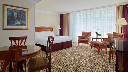 Suite des Leipzig Marriott Hotel mit großem Bett, Schreibtisch sowie Tisch mit Stühlen.