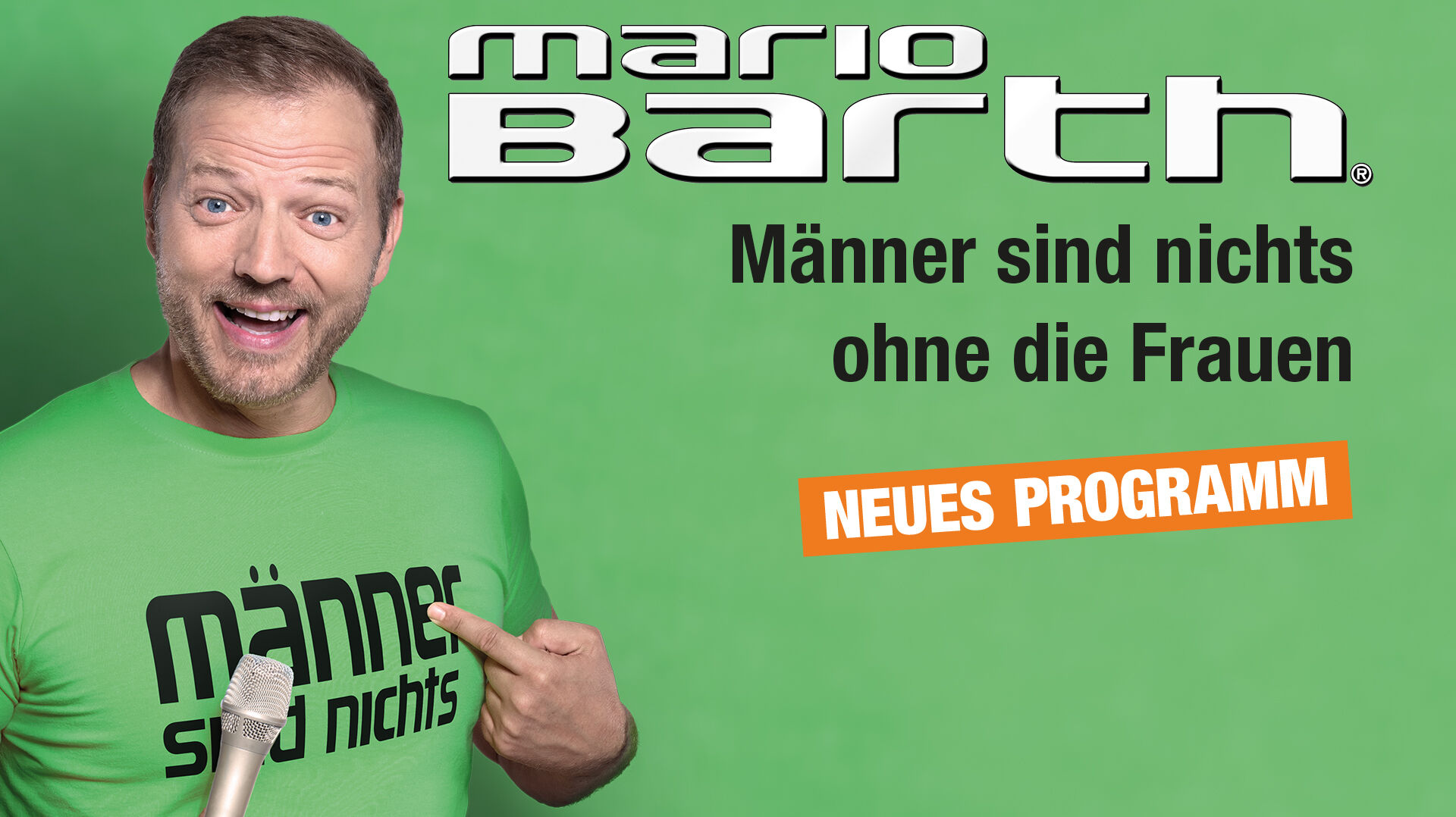 Mario Bath hat ein Mikro in der Hand und zeigt auf sein T-Shirt, auf dem steht "Männer sind nichts".
