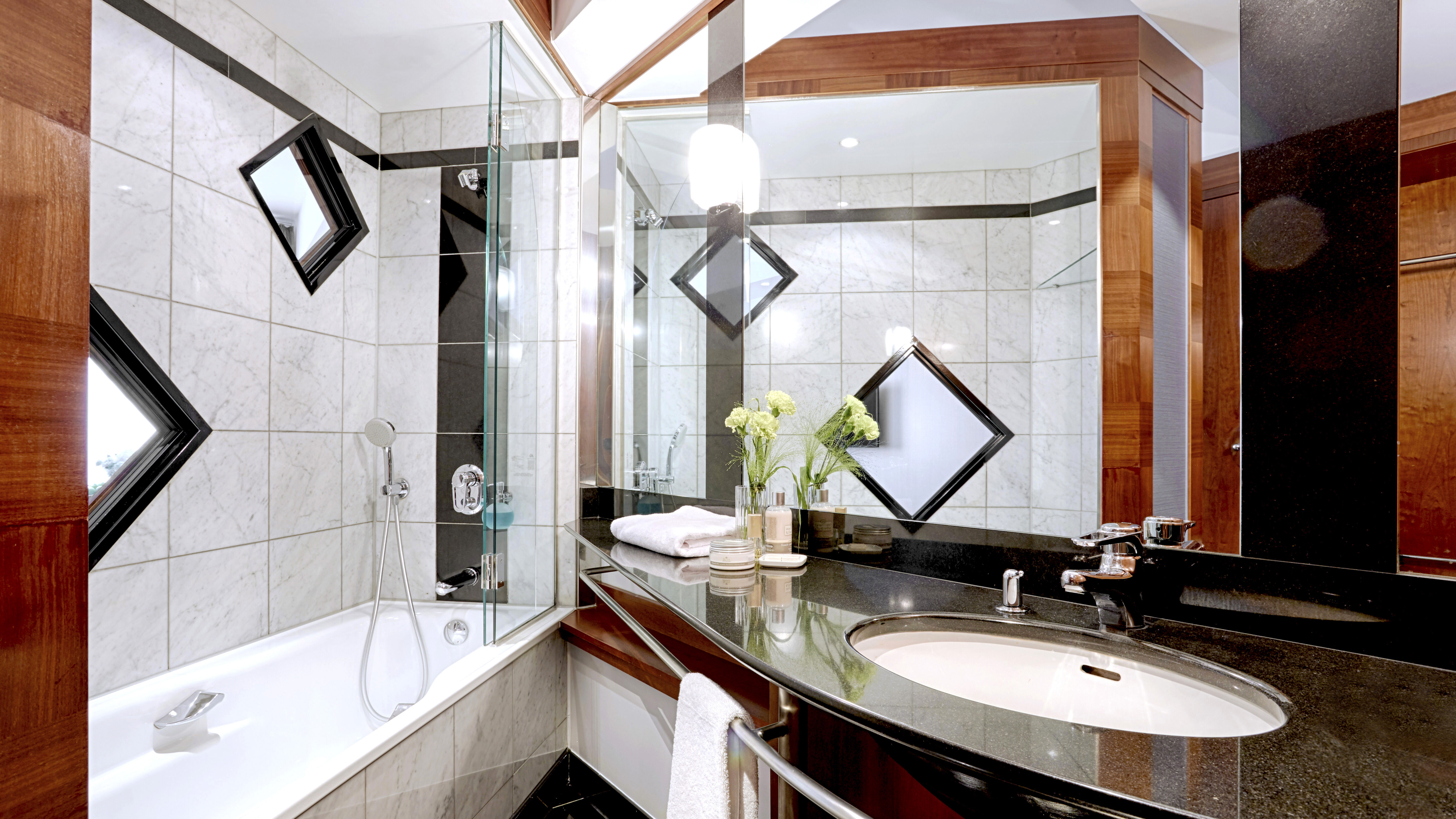 Badezmmer mitWaschbecken, großem Spiegel und Badewanne mit Dusche.