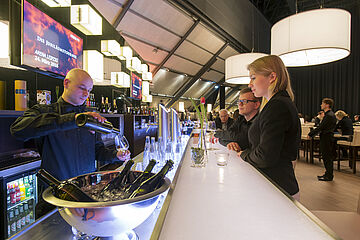 Kellner schenkt Getränke an einer modernen Bar aus.