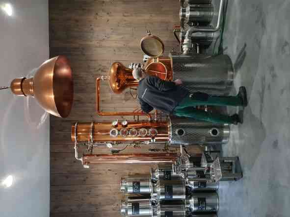 Ein Mann vor einer Destillationsanlage. 