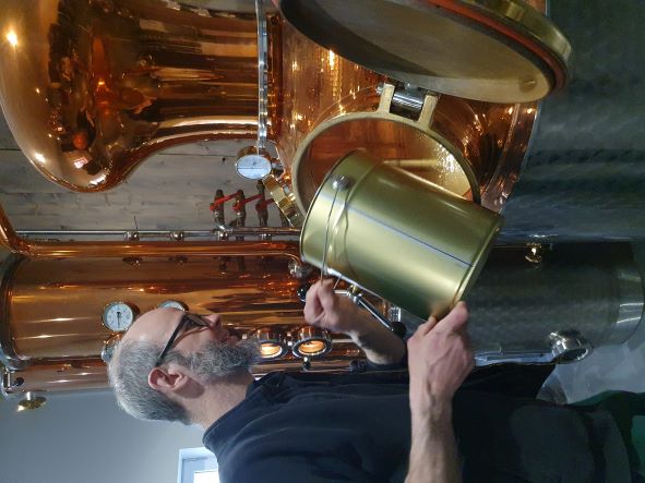 Ein Mann gibt Honig in eine Destillationsanlage. 