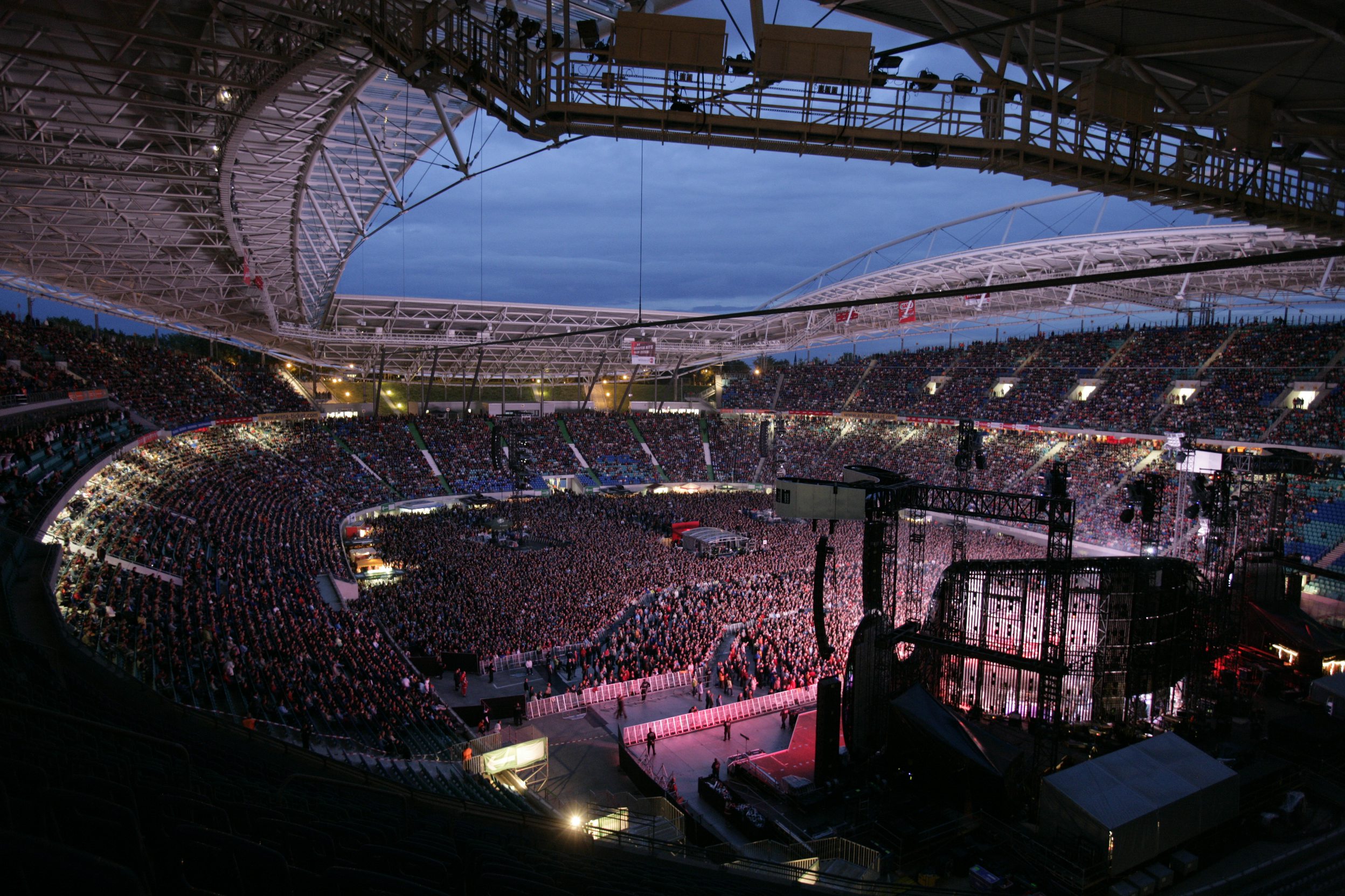 Menschenmasse vor einer beleuchteten Bühne in der Red Bull Arena am Abend.